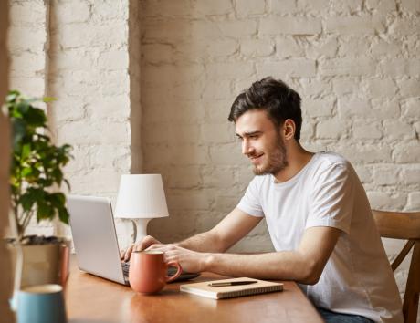 A young man typing on a laptop to illustrate adding coursework to your resume