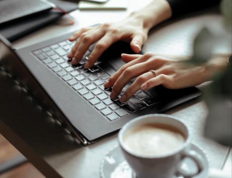 Hvordan skrive CV: person som sitter ved et skrivebord og jobber med CV på laptop