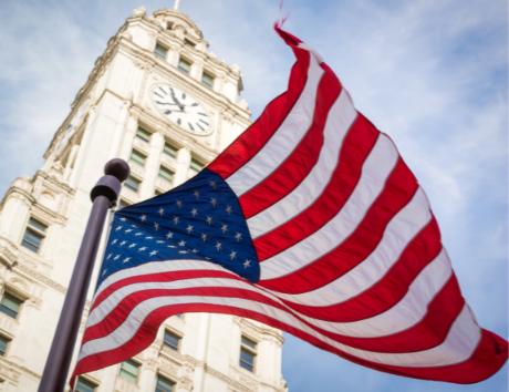 Top dream jobs in America are depicted by an image of the American flag blowing in the wind with a larger building and blue sky in the background.