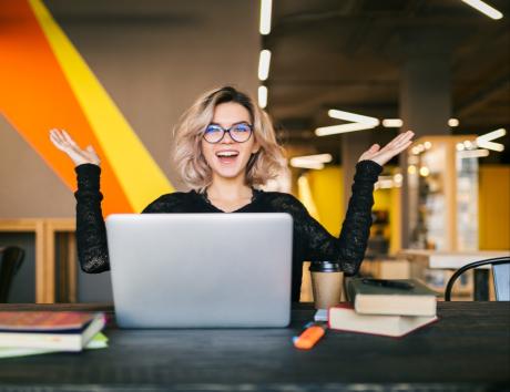 Woman smiling while using laptop to illustrate resume structure