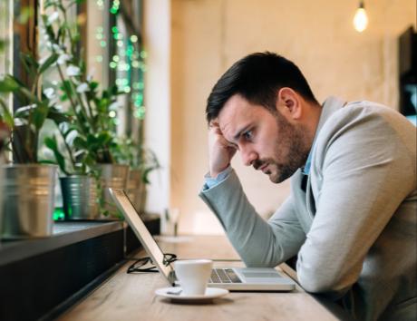 Man looking down at computer with disappointed face to illustrate gaps in a CV