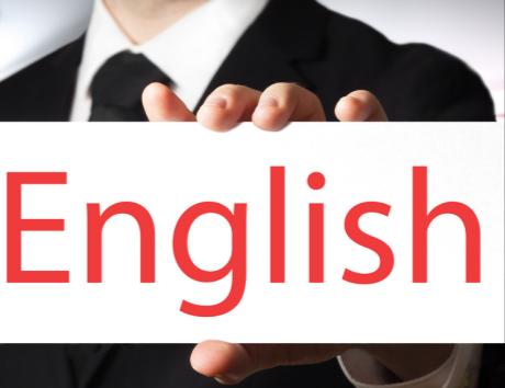 Ucięte ujęcie sylwetki mężczyzny ubranego w biurowe ubranie trzymającego białą plakietkę z czerwonym napisem „English”.