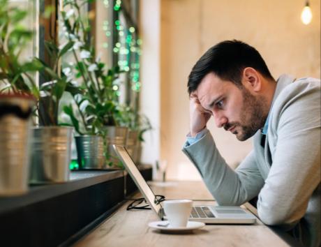 Man looking at computer while writing a resume with gaps in employement