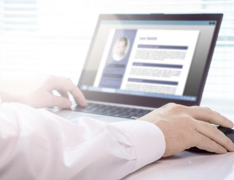 Persona seduta alla scrivania mentre modifica il curriculum vitae sul laptop, a illustrazione di come scrivere un CV.
