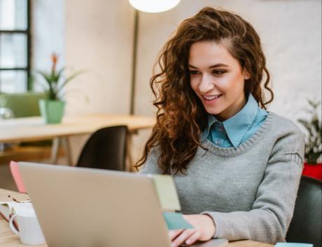 Woman smiling while using a laptop to illustrate a CV with no experience
