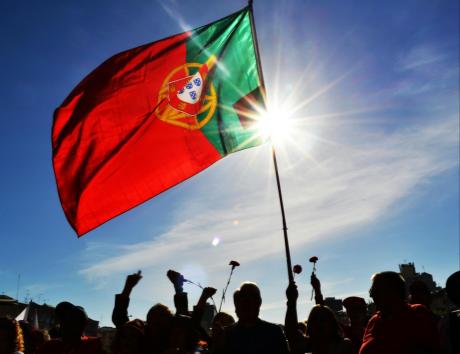 Bandeira de Portugal diante de um céu azul, ilustrando a elaboração de um currículo para o mercado de trabalho português.