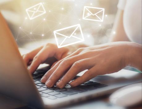 mani che scrivono su tastiera di computer con grafiche di buste di lettere per illustrare email per inviare cv